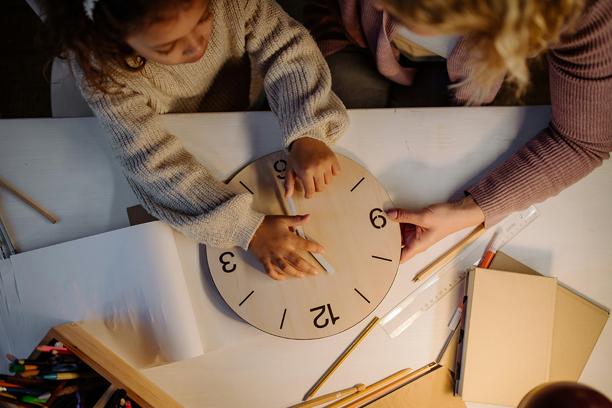 child and parent setting a clock for daylight saving